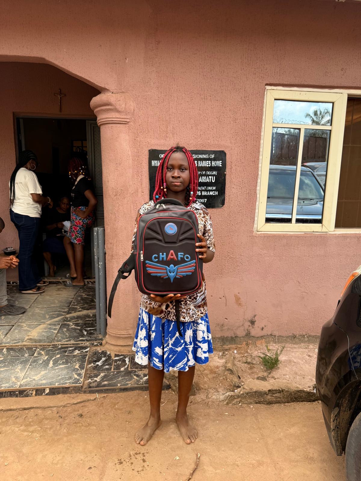 A girl holding a backpack outside the orphanage during the December visit.