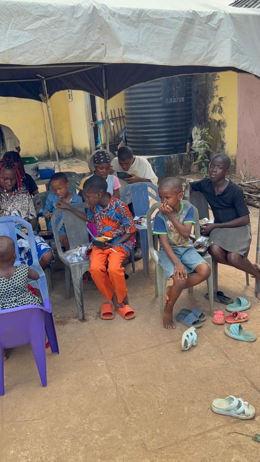 Children seated outside under a canopy during the December orphanage visit.