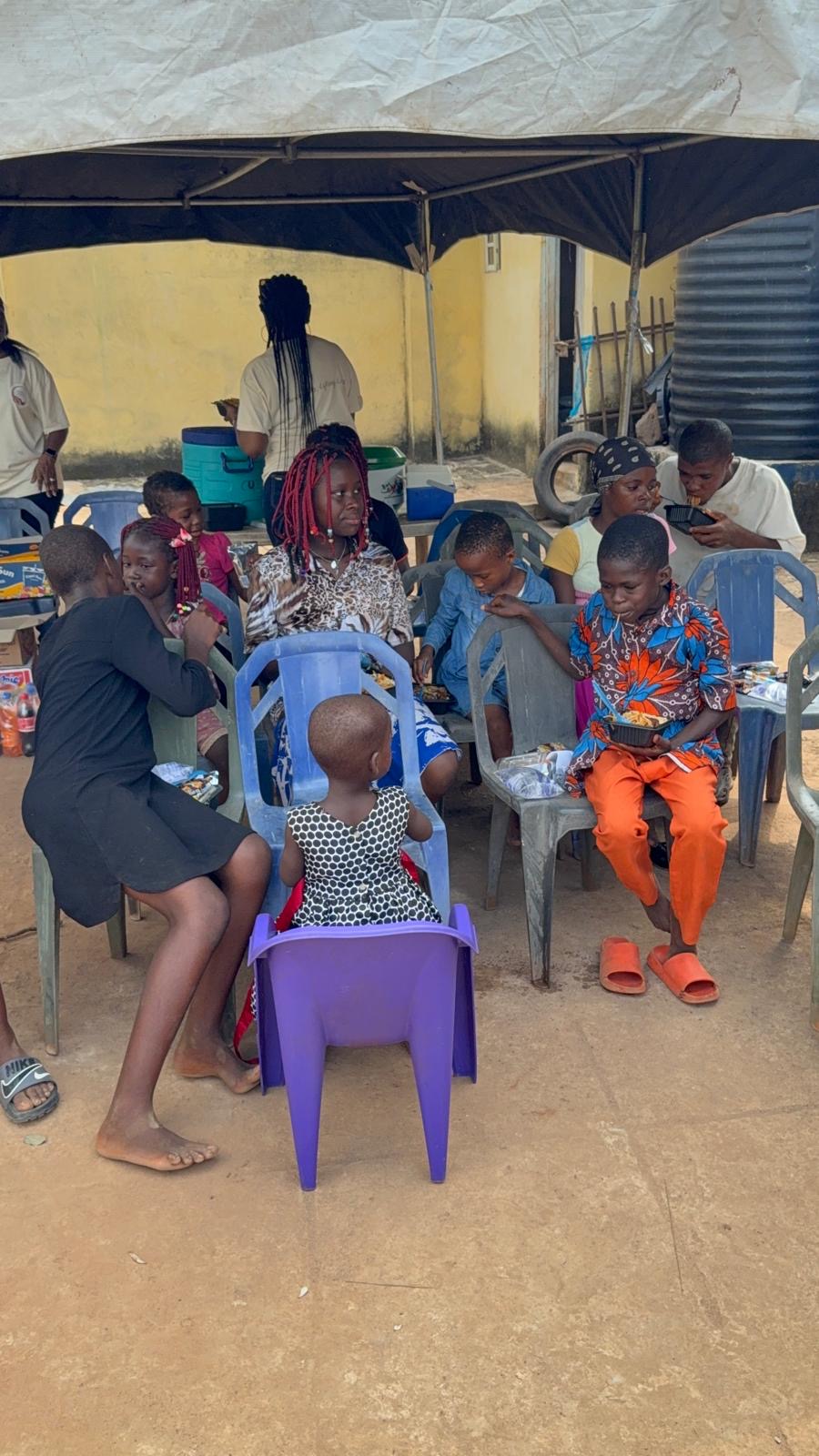 Children seated outside eating during the December community visit.