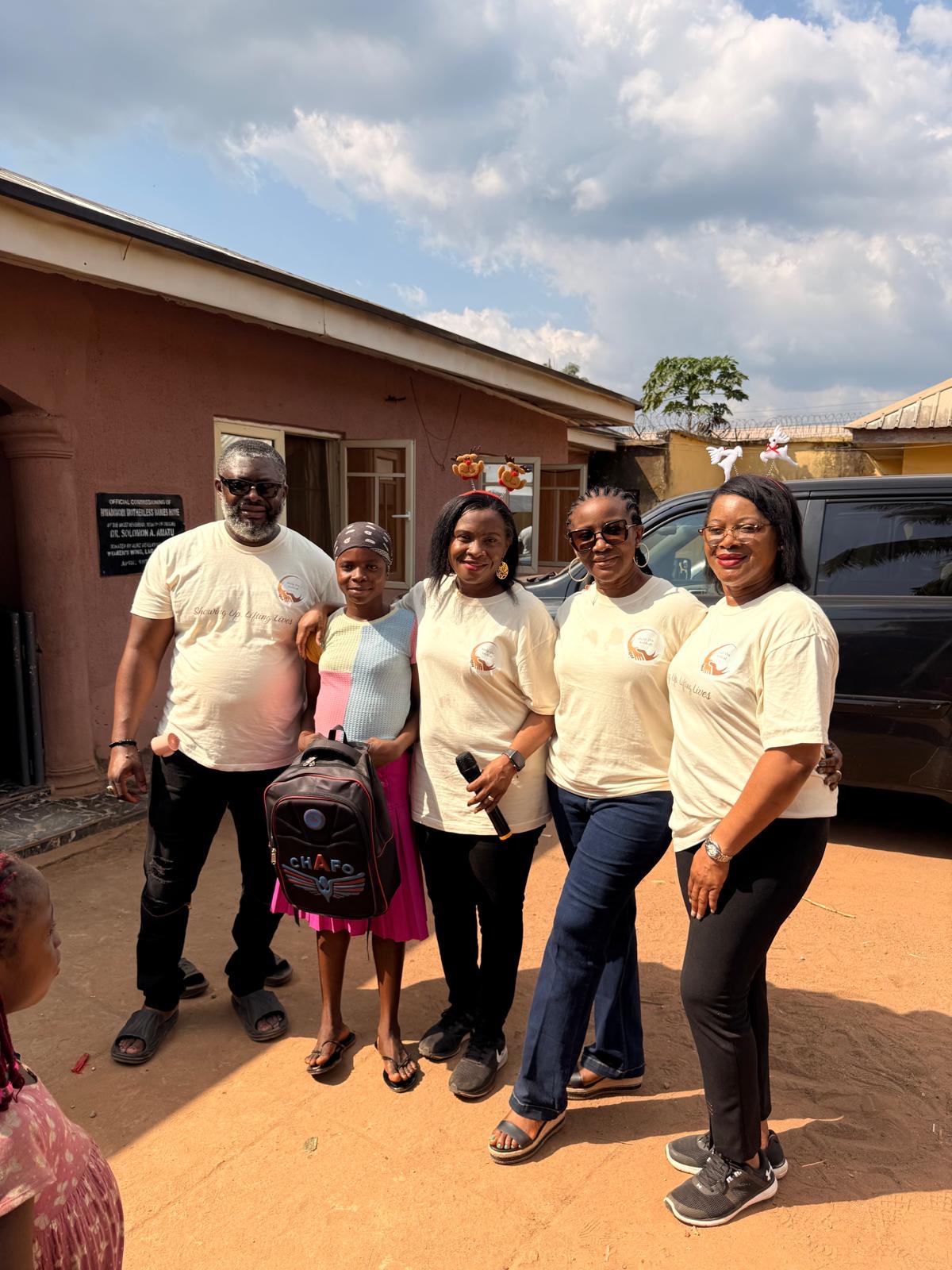 Help On Arrival team members standing with a child and backpack outside during the December 2025 orphanage visit.