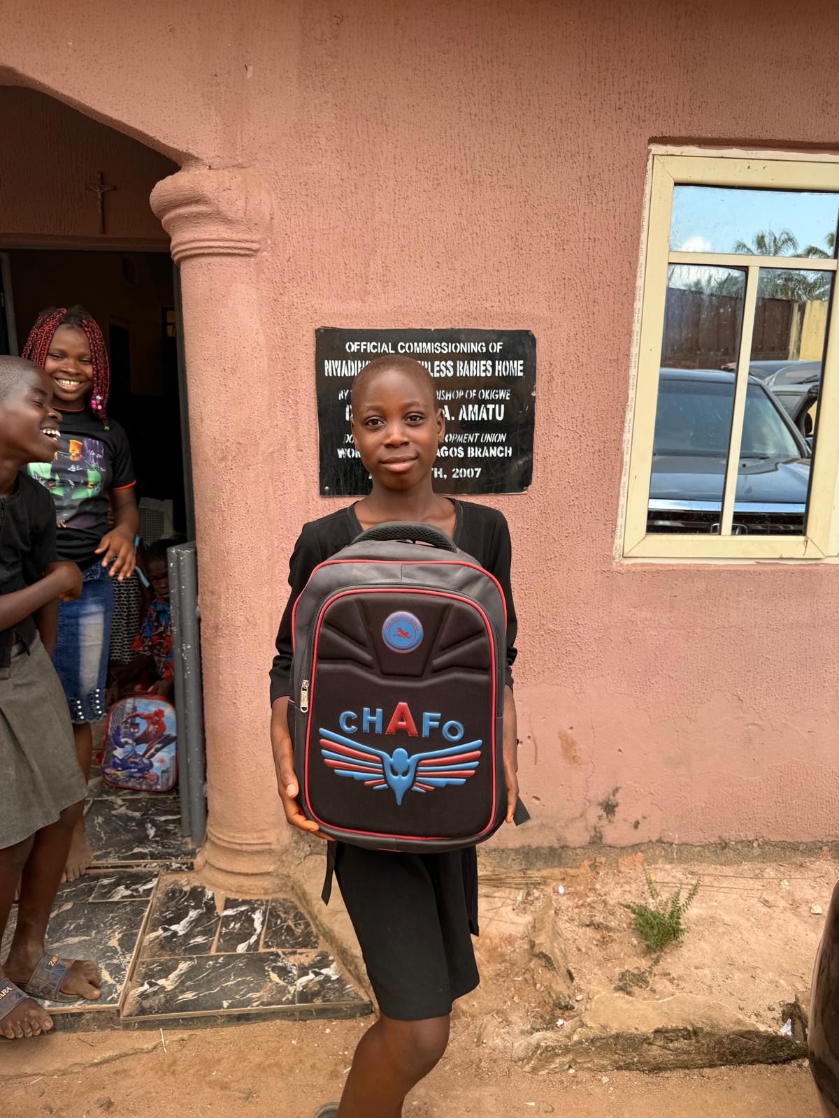 A child holding a donated backpack outside the orphanage during the Help On Arrival visit